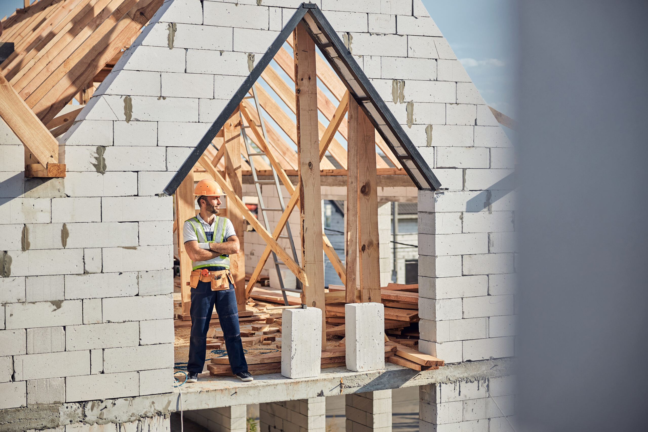 Full-length photo of a qualified contractor wearing safety clothes and standing in the unfinished building